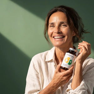 Donna sorridente con il flacone di DuoWell D3+K2 di Naturadika